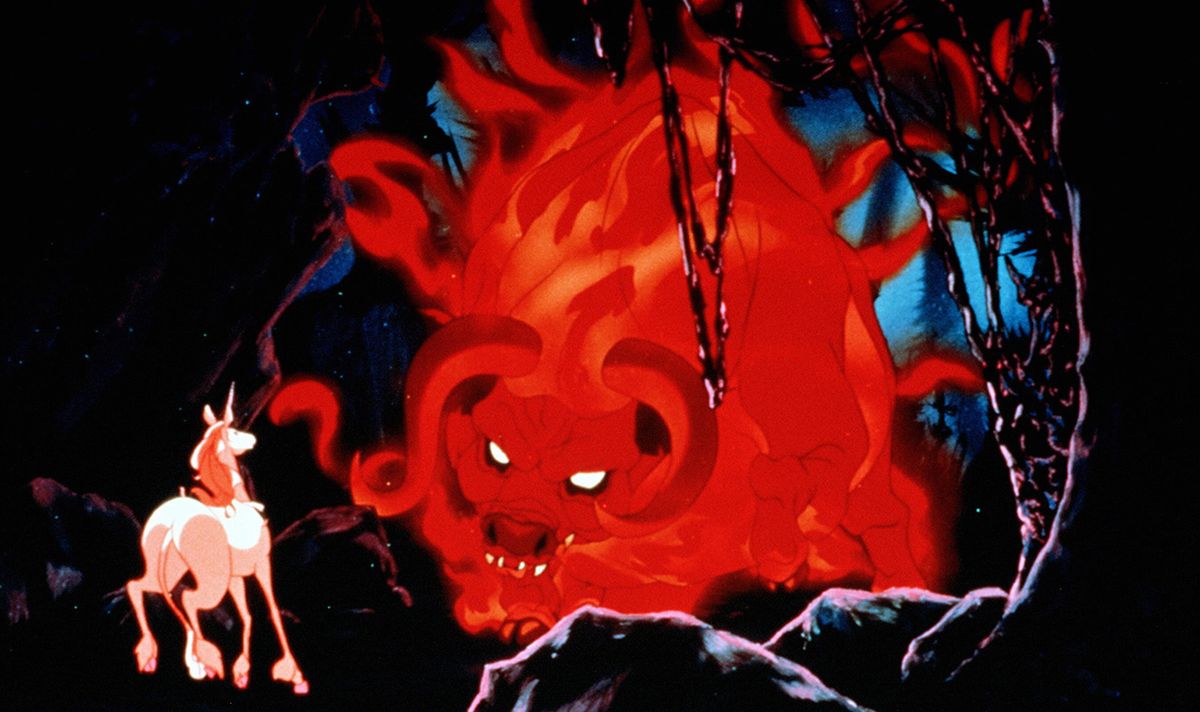 A glowing red demonic bull with curved horns advances toward a small white unicorn in a dark cavern surrounded by twisted branches and blue-tinted rock formations